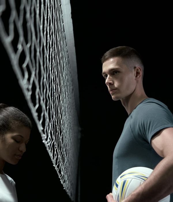 Athletic man performing a focus-based strength exercise in a dark studio.